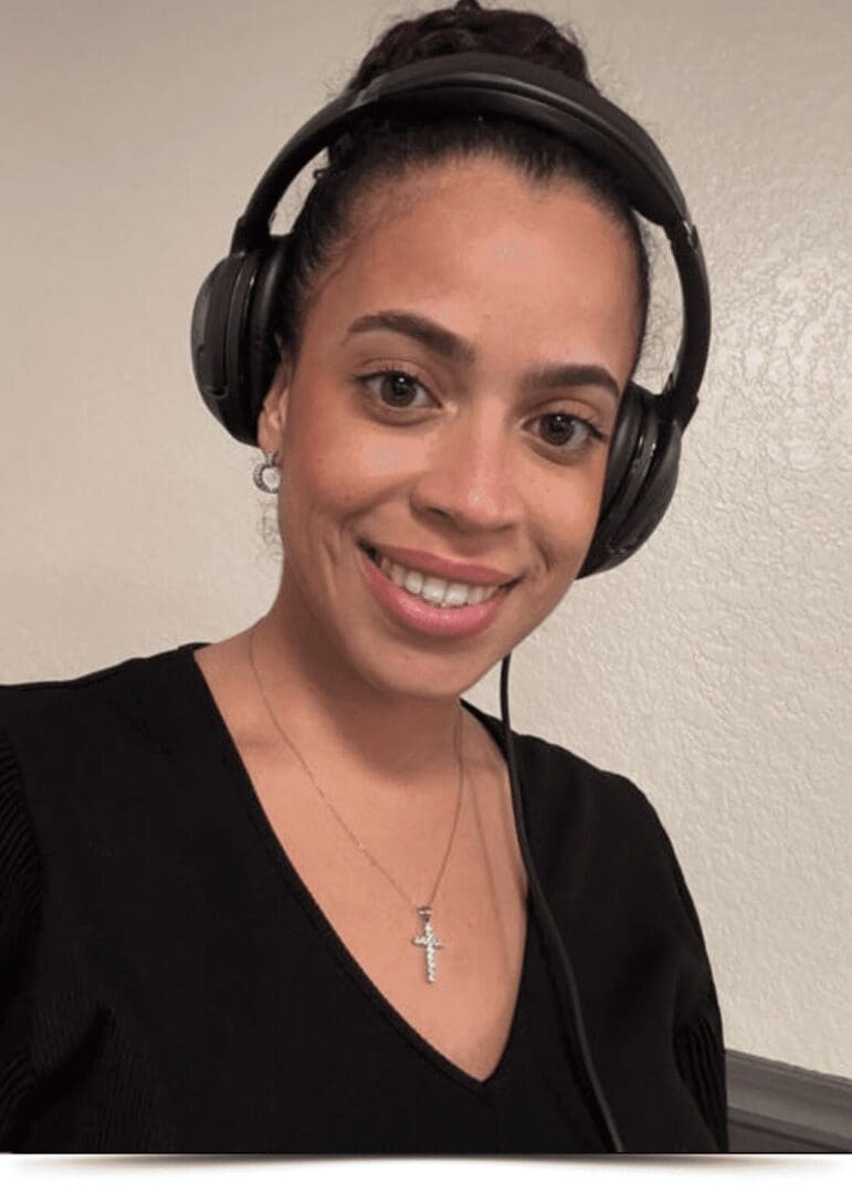 Meet DJ Keynah, smiling with headphones covering her ears, a black blouse and a cross on a necklace.